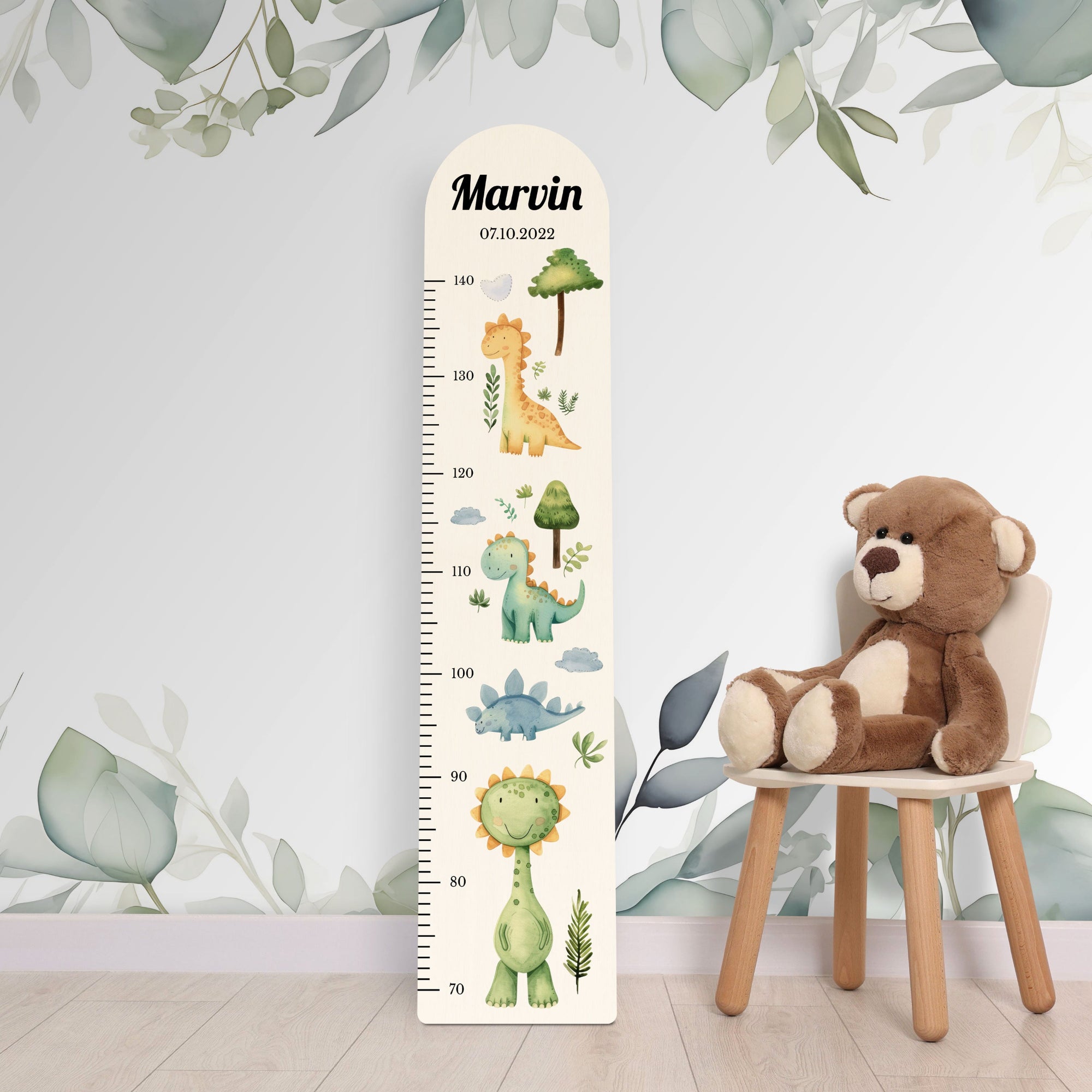 Personalisierte Messlatte aus Holz für Jungen oder Mädchen mit Dinos vor einer Kinderzimmerwand. Personalisierte Messlatte aus Holz für Jungen oder Mädchen mit Dinos vor einer Kinderzimmerwand.