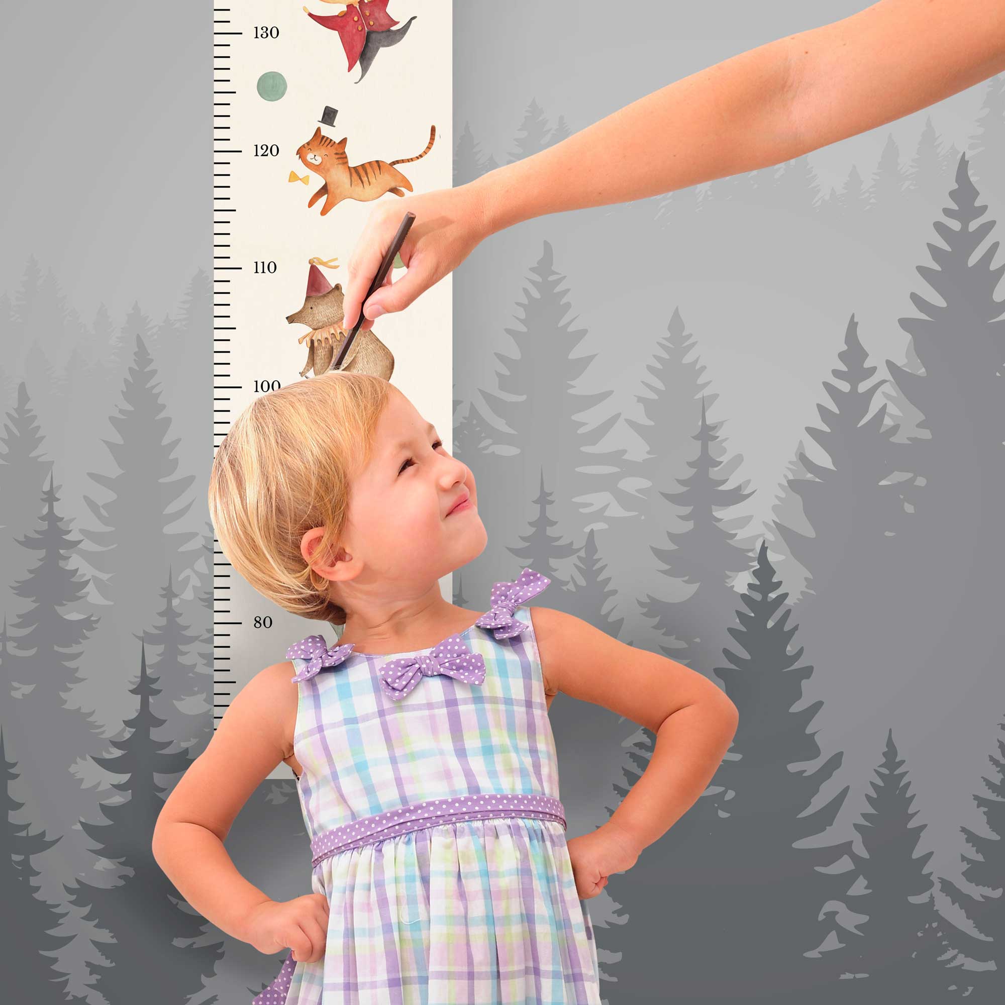 Mädchen steht vor der personalisierten Messlatte und misst seine Größe Mädchen steht vor der personalisierten Messlatte und misst seine Größe