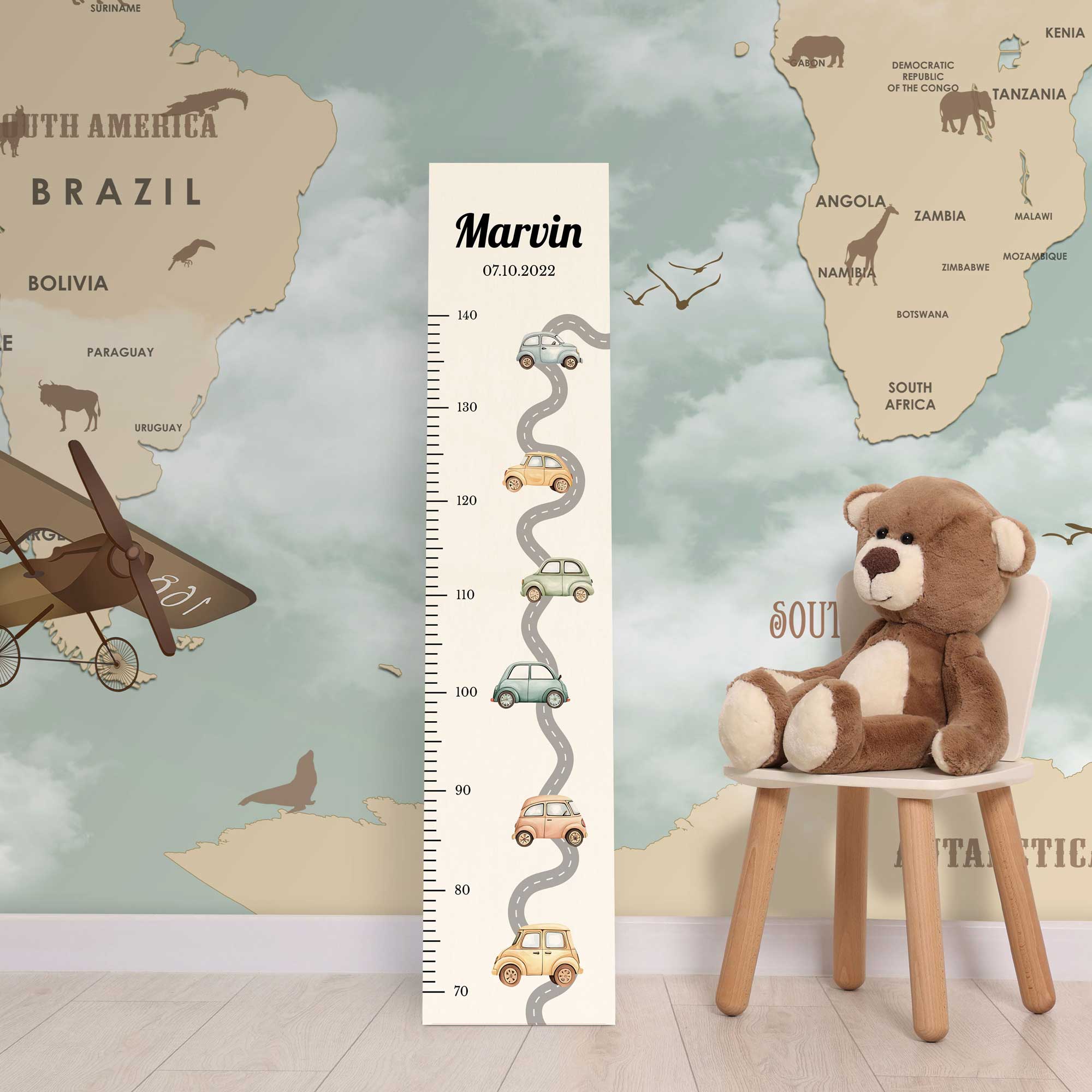 Personalisierte Messlatte aus Holz für Jungen mit Autos vor einer Kinderzimmerwand.