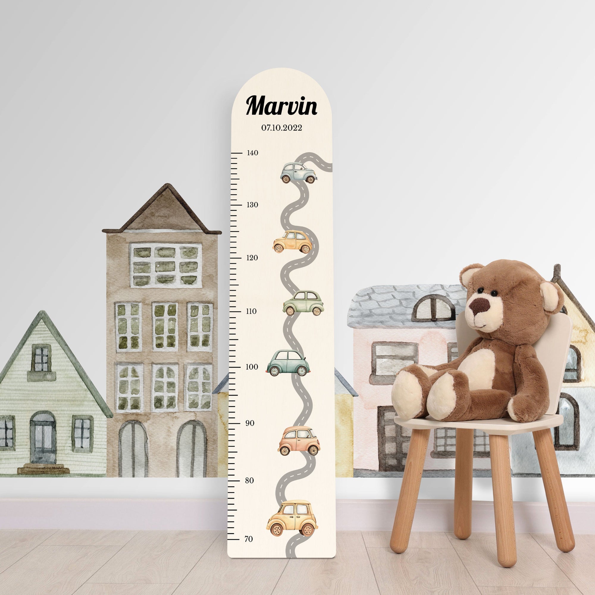 Personalisierte Messlatte aus Holz für Jungen mit Autos vor einer Kinderzimmerwand.