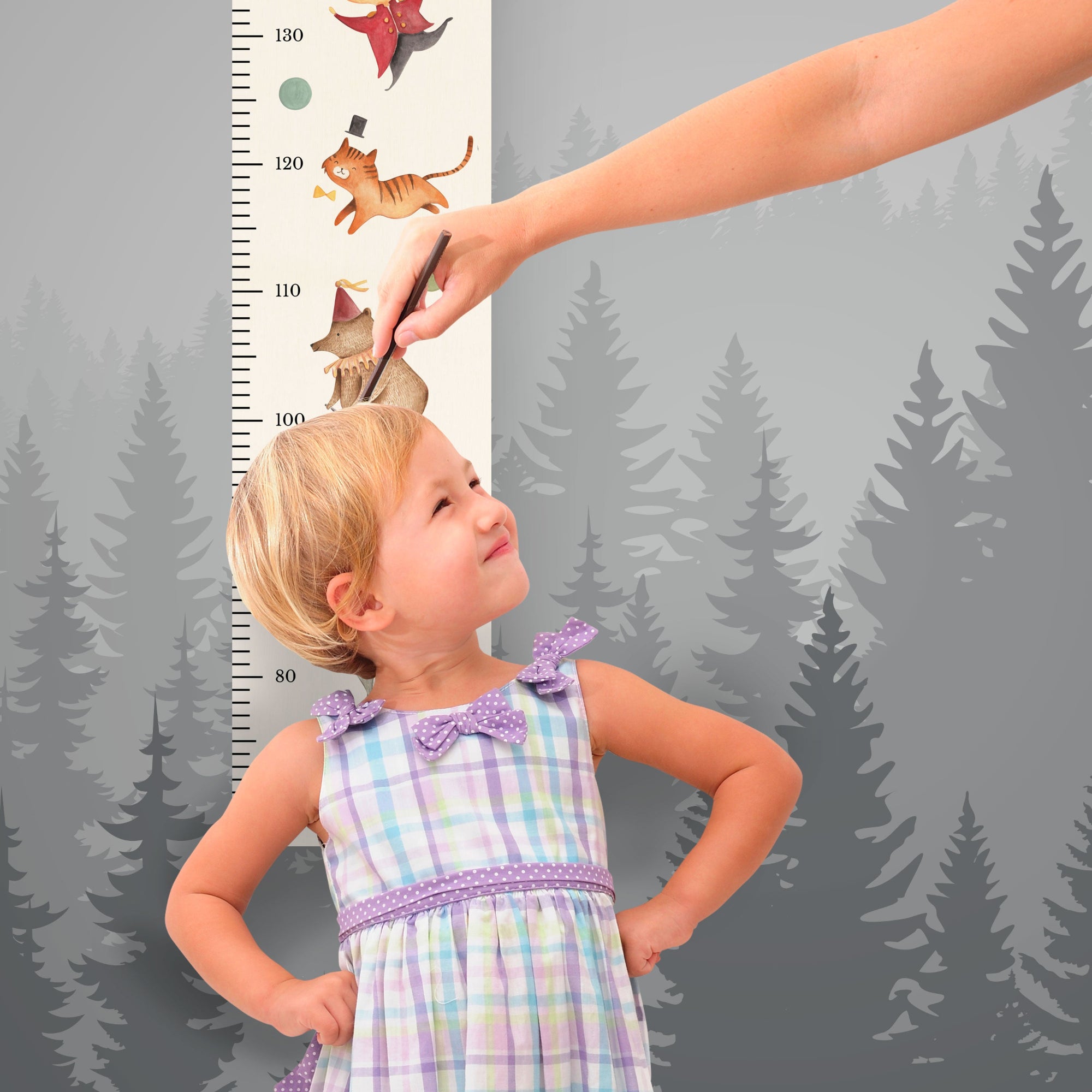 Mädchen steht vor der personalisierten Messlatte und misst seine Größe